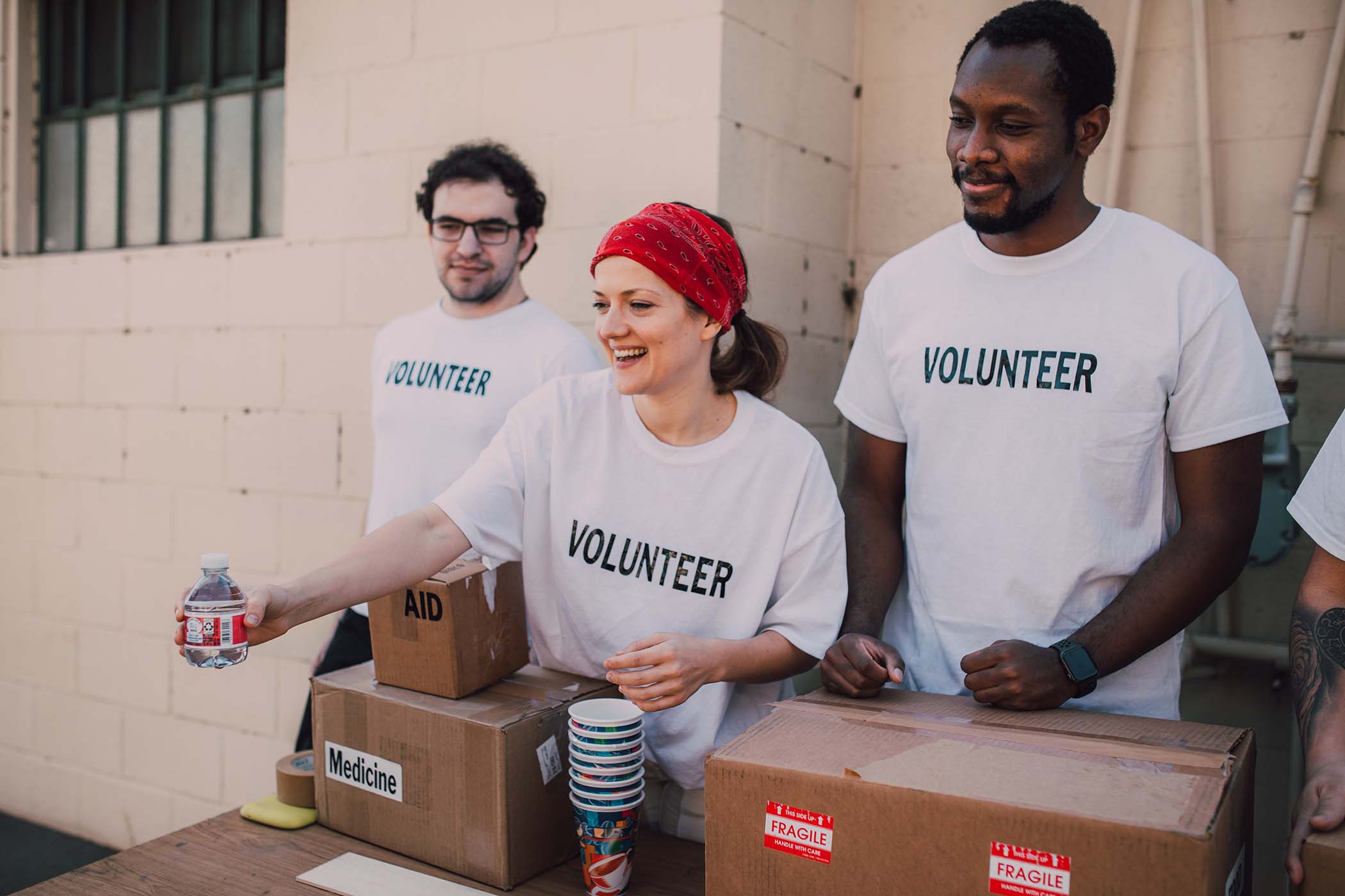 three volunteers hand out water bottles at a table